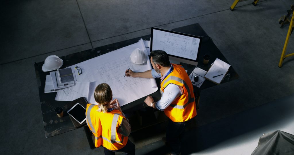 High-angle shot of construction designer and construction consultant going over a blueprint together in an industrial place of work