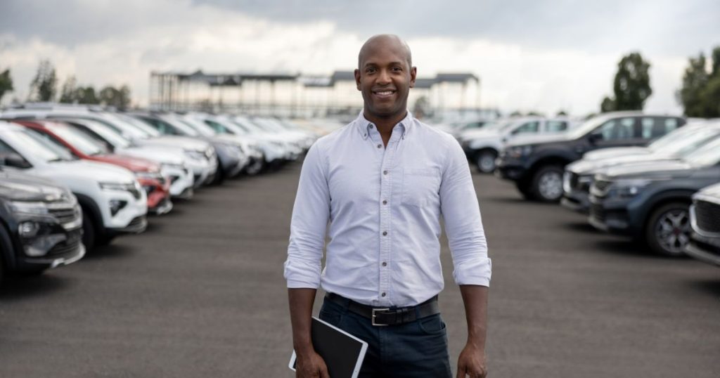 Facility Owners Standing in parking lot with efficiency technology after auto dealership renovation